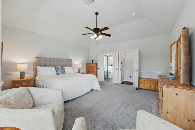 Carpeted bedroom featuring vaulted ceiling, ceiling fan, and connected bathroom | Image 21