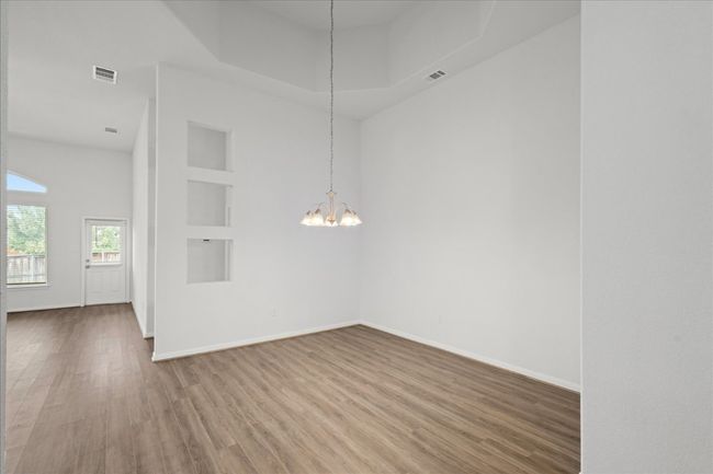 Unfurnished dining area with wood finished floors, a chandelier, baseboards, and built in shelves | Image 18