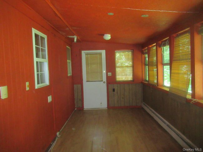 Unfurnished sunroom featuring lofted ceiling and a baseboard radiator | Image 12