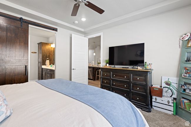 Bedroom with ensuite bathroom, a barn door, carpet floors, and a ceiling fan | Image 34