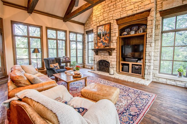 Living room with a fireplace, high vaulted ceiling, wood finished floors, and a healthy amount of sunlight | Image 4