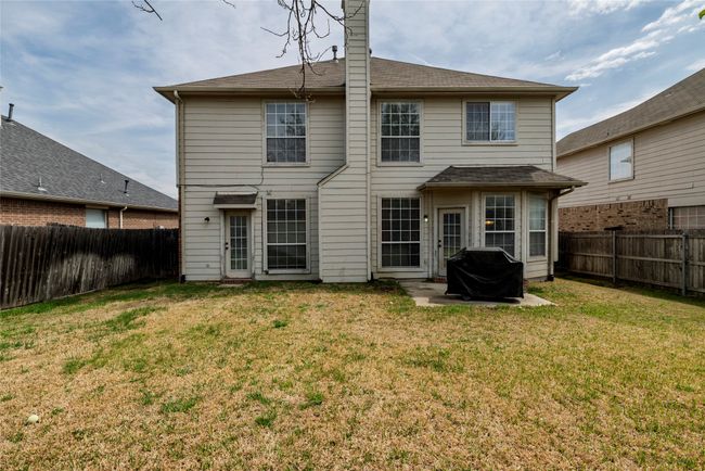 Back of house featuring a fenced backyard, a chimney, and a lawn | Image 32