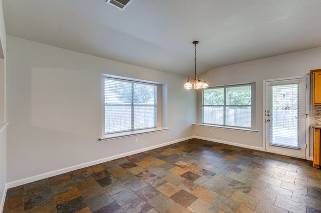 Unfurnished room featuring dark stone finish floors, a chandelier, plenty of natural light, and lofted ceiling | Image 10