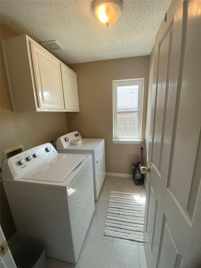 Laundry room with cabinet space, a textured ceiling, visible vents, washing machine and clothes dryer, and light tile patterned floors | Image 28