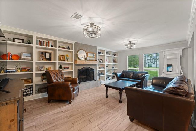 This living room features elegant built-in shelves and a cozy fireplace. Large windows provide ample natural light. Perfect for relaxation and entertaining. | Image 6