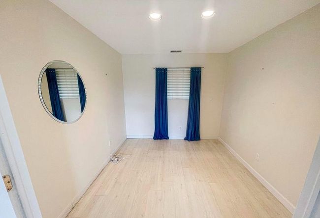Empty room with light wood finished floors, baseboards, visible vents, and recessed lighting | Image 23