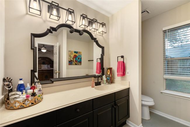 In the en-suite, expansive counters, bold black cabinetry, and a unique framed mirror bring character to the space. | Image 13