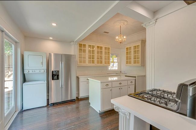 Kitchen featuring stainless steel fridge with ice dispenser, estacked washer and dryer, a chandelier, decorative backsplash, and dark wood-style floors | Image 8