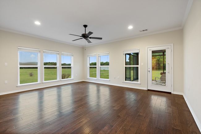 Empty room with dark wood-style floors, visible vents, a ceiling fan, and a healthy amount of sunlight | Image 15