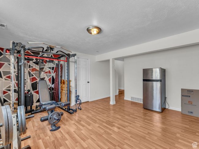 Exercise area with wood finished floors, a textured ceiling, and baseboards | Image 19