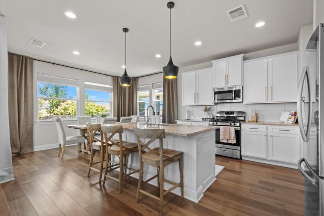 Kitchen with stainless steel appliances, backsplash, dark wood-type flooring, an island with sink, and recessed lighting | Image 8