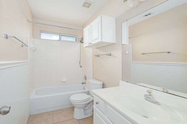 Bathroom with a wainscoted wall, vanity, shower / washtub combination, and tile patterned flooring | Image 22