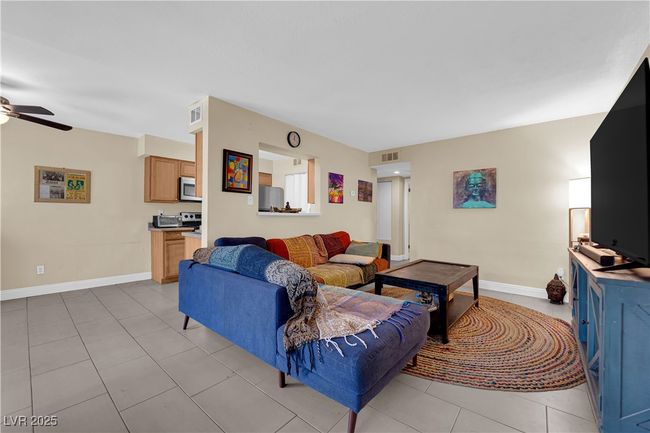 Living room with light tile patterned flooring, a ceiling fan, visible vents, and baseboards | Image 6