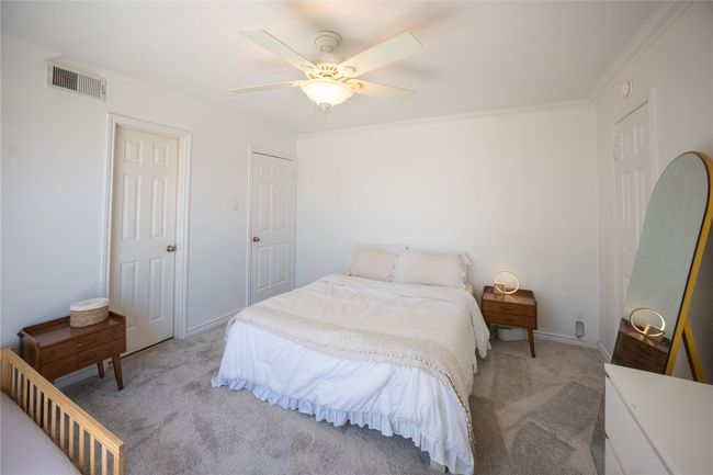 Bedroom featuring light colored carpet, ceiling fan, crown molding, and visible vents | Image 10