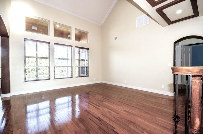Unfurnished living room featuring ornamental molding, dark wood finished floors, baseboards, and high vaulted ceiling | Image 9