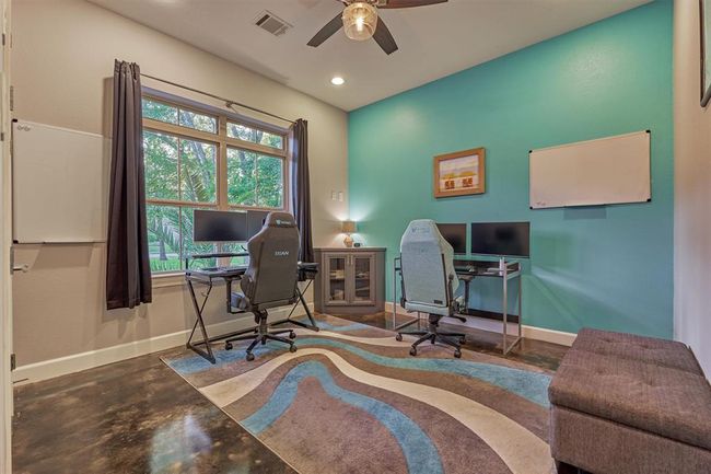 The first guest bedroom, currently used as a home office, features a large window that fills the space with natural light and offers a charming view of the front yard. | Image 9