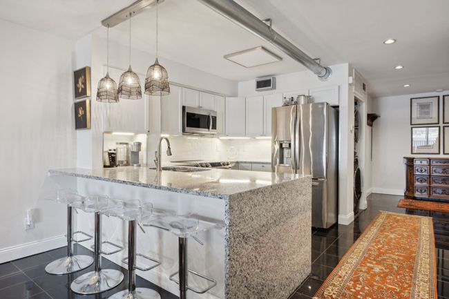 Open kitchen with bar seating facing entryway/foyer. | Image 10