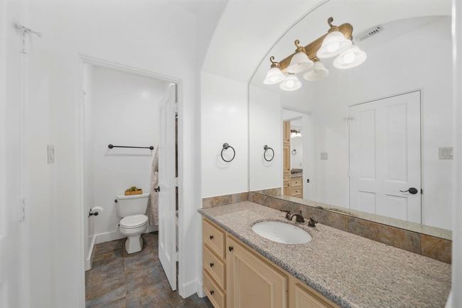 Serving as the home's fourth full bath and situated just between the third & fourth bedrooms, features include a painted cabinet with a granite counter top & tiled back splash, wall mounted mirror & lighting, a walk-in wardrobe storage closet & tile flooring. | Image 35