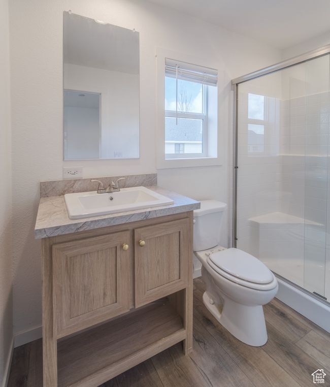 Bathroom featuring vanity, a shower stall, toilet, and wood finished floors | Image 8