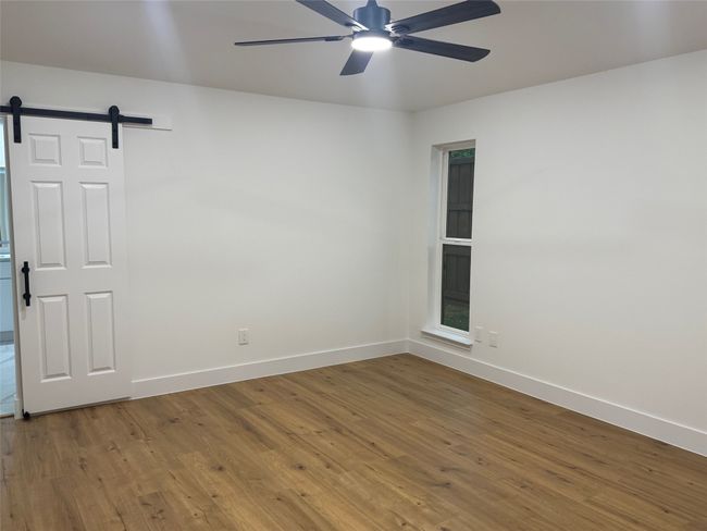 Nice-size primary bedroom with barn door leading into luxurious bathroom | Image 11