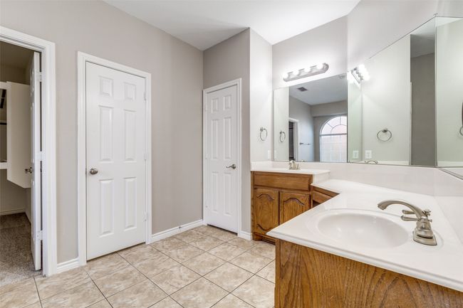 Full bath featuring double vanity, tile patterned floors, baseboards, and a sink | Image 15