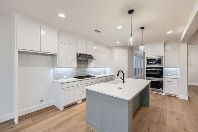 Kitchen featuring under cabinet range hood, a sink, stainless steel appliances, and light wood-style floors | Image 8