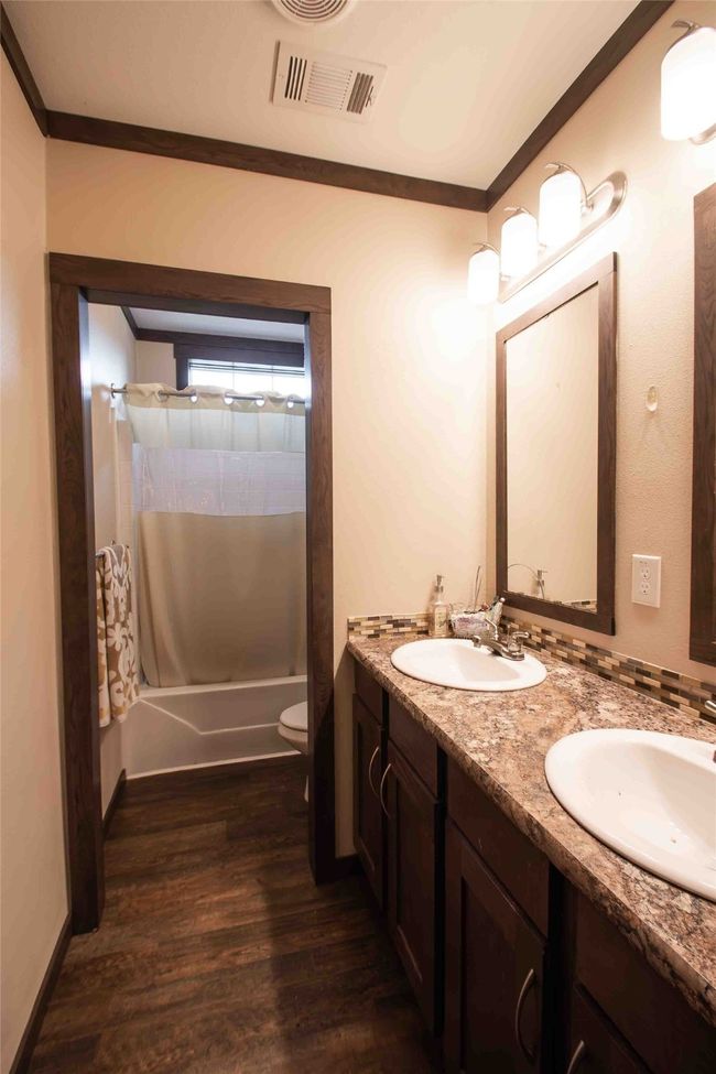 Full bath featuring toilet, double vanity, wood finished floors, shower / tub combo, and ornamental molding | Image 23