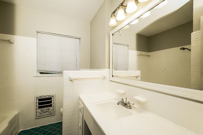 Full bathroom with heating unit, tile walls, vanity, a wainscoted wall, and tile patterned floors | Image 21