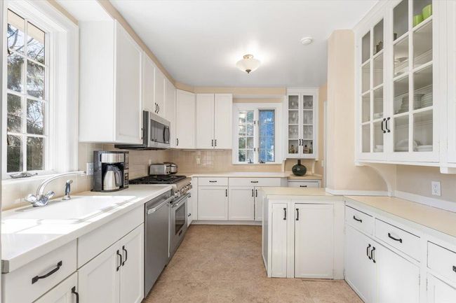 Kitchen featuring a sink, white cabinets, light countertops, appliances with stainless steel finishes, and decorative backsplash | Image 9