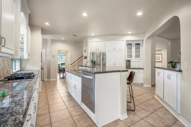 The island kitchen offers stainless steel appliances, tons of counter top place, a diagonal tiled backsplash and cabinetry which is light and bright. | Image 18