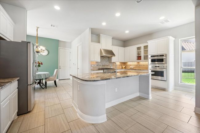 Kitchen with wall chimney range hood, a sink, appliances with stainless steel finishes, and visible vents | Image 10