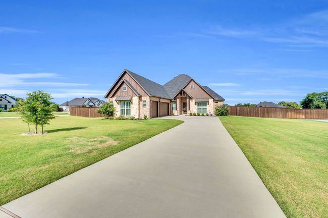 View of front of home featuring a garage, driveway, brick siding, stone siding, and roof with shingles | Image 34