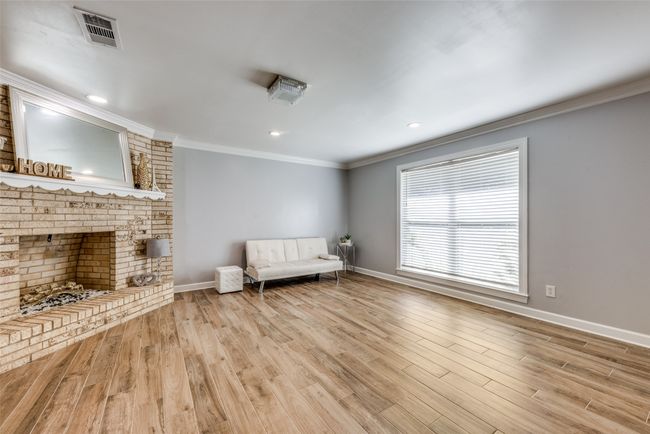 Unfurnished room with ornamental molding, wood finished floors, a fireplace, and recessed lighting | Image 7