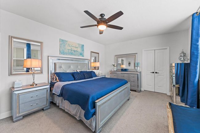 The spacious primary bedroom boasts mirrored furnishings, soft lighting, ample room for a king-sized bed, sitting area, and storage options | Image 12