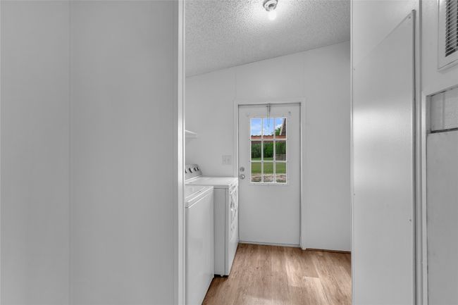 Laundry area featuring washer and clothes dryer, a textured ceiling, and light wood-type flooring | Image 17