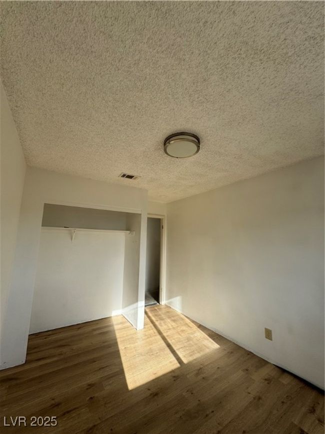 Unfurnished bedroom featuring wood finished floors, a textured ceiling, and a closet | Image 16