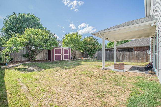 View of yard featuring a fenced backyard, a storage unit, and an outbuilding | Image 22