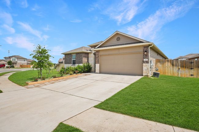 View of front of property featuring an attached garage, driveway, stone siding, and brick siding | Image 36