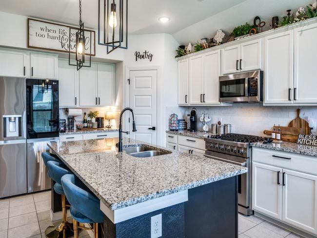 Kitchen with stainless steel appliances, light tile patterned floors, a sink, decorative backsplash, and a kitchen island with sink | Image 15
