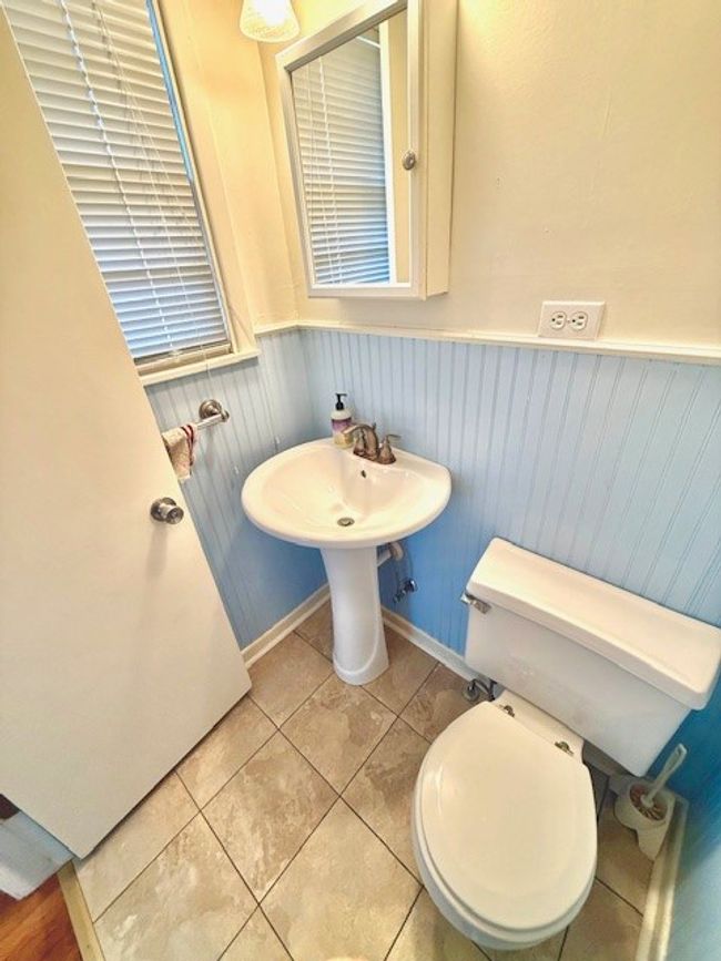 Half bathroom with toilet, tile patterned floors, and wainscoting | Image 11