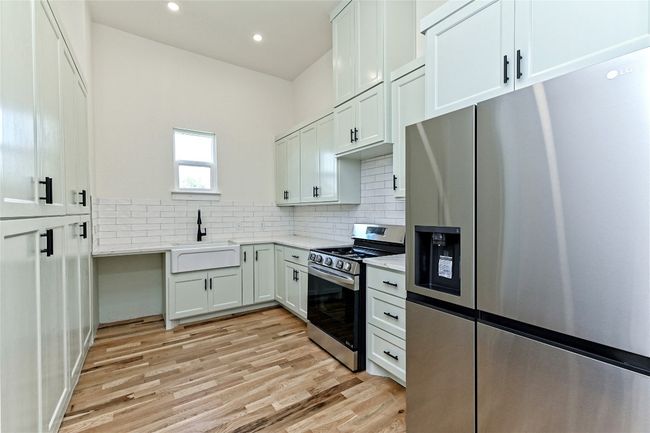 Kitchen with appliances with stainless steel finishes, light wood-type flooring, decorative backsplash, recessed lighting, and light stone countertops | Image 30