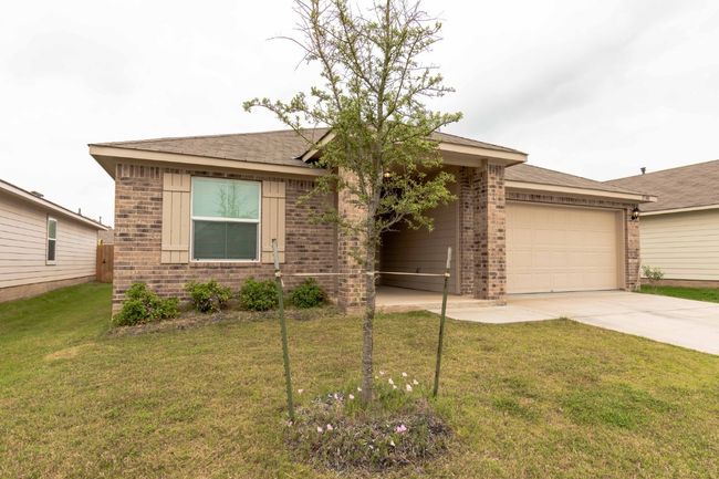 View of front facade with brick siding, an attached garage, driveway, a front lawn, and roof with shingles | Image 21