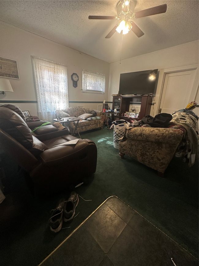 Living room with ceiling fan and a textured ceiling | Image 4