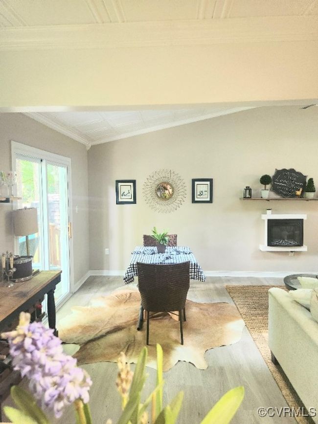 Living area featuring wood finished floors, ornamental molding, and a glass covered fireplace | Image 8
