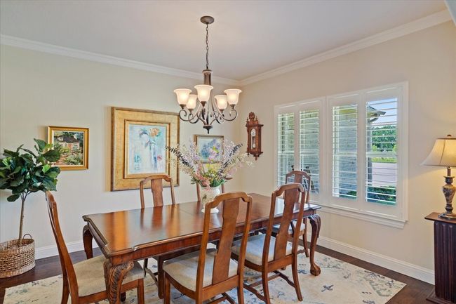 Dining area with crown molding, baseboards, a chandelier, and dark wood-type flooring | Image 4