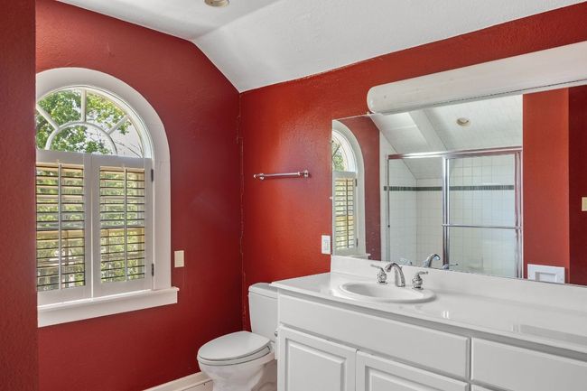 Full bathroom featuring a textured wall, vaulted ceiling, plenty of natural light, a shower stall, and vanity | Image 29