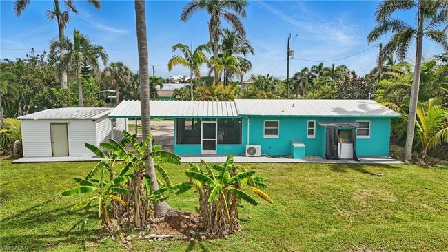 Back of property featuring a sunroom, a lawn, a metal roof, and a shed | Image 36
