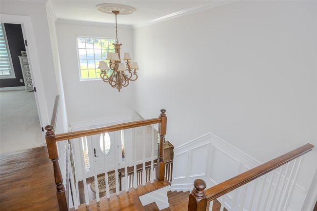 Stairs with a chandelier, ornamental molding, a decorative wall, wood finished floors, and a wainscoted wall | Image 19