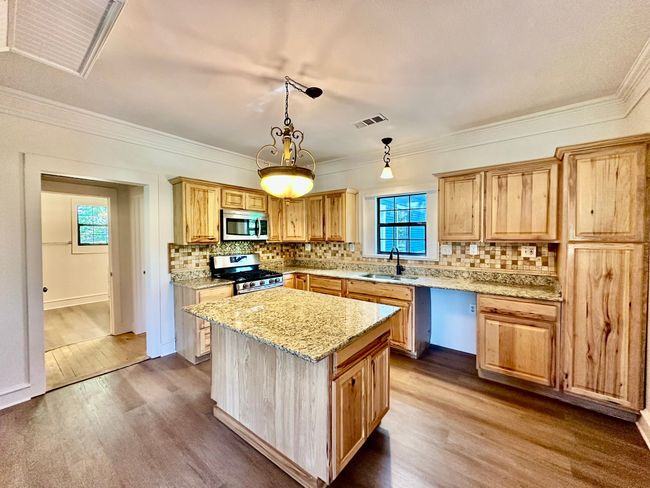 Kitchen with dark wood-style flooring, decorative backsplash, a center island, appliances with stainless steel finishes, and crown molding | Image 20