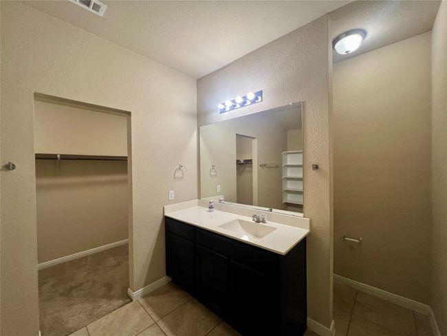 Primary bathroom with a spacious closet, vanity, tile patterned flooring, and baseboards | Image 17
